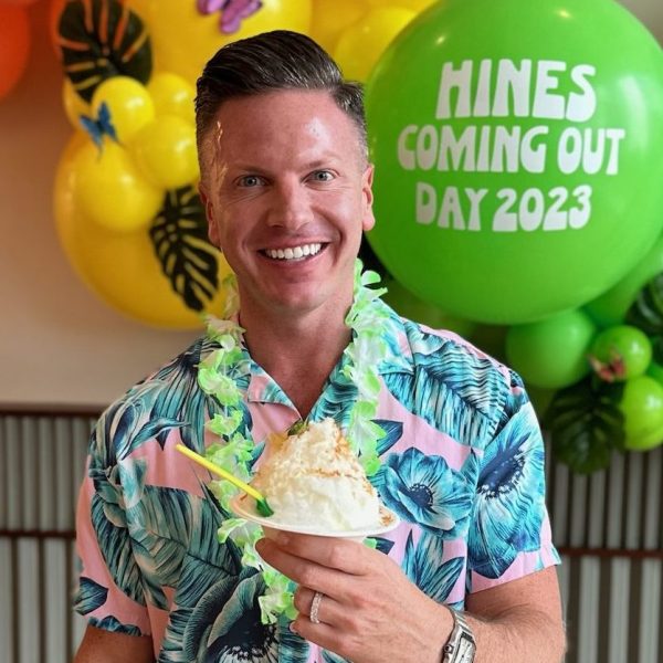 Man in Hawaiian print shirt at party smiling and eating Sno'd Shaved Ice snow cone