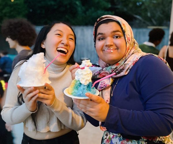 Two girls laughing at outdoor event eating Sno'd Shaved Ice snow cones